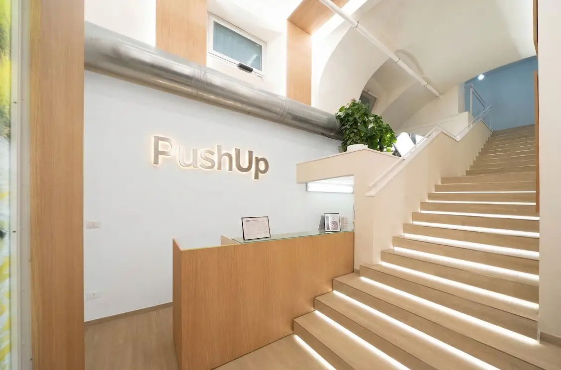 La reception di Push Up con la scritta in legno e la scala illuminata
